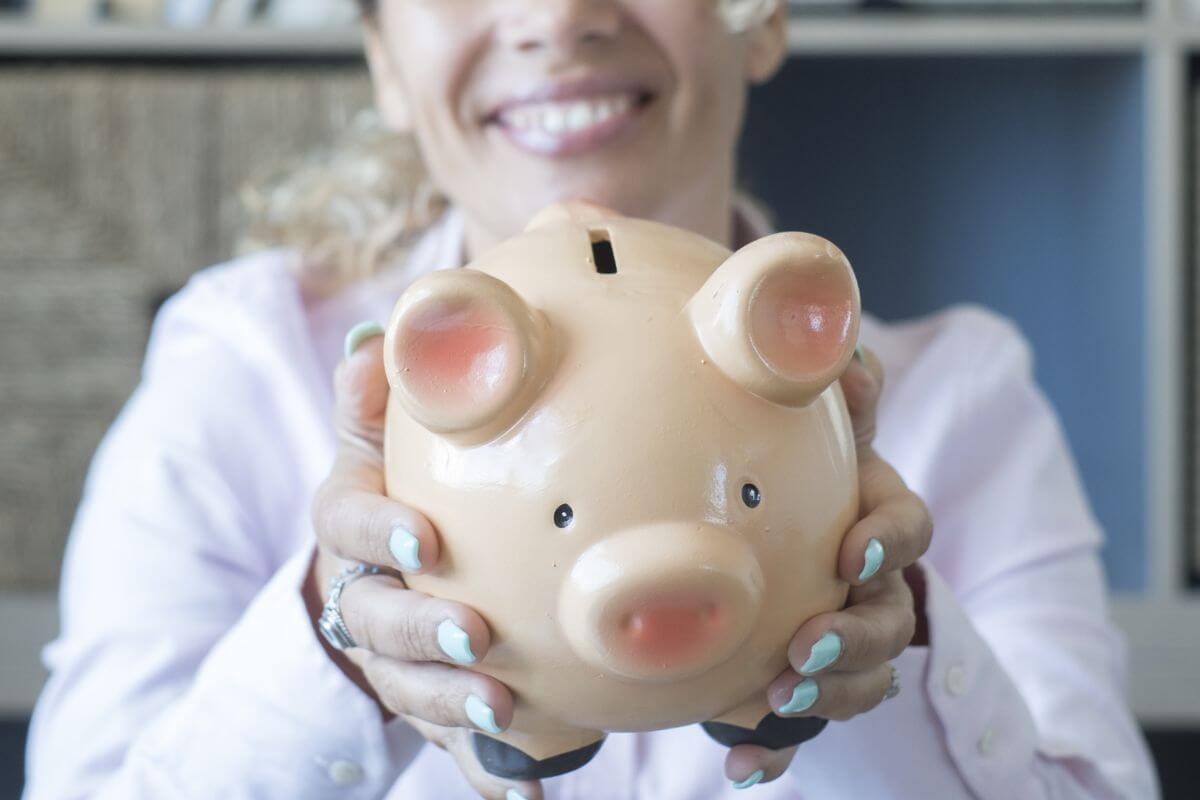 An image shows a woman holding a piggy bank.