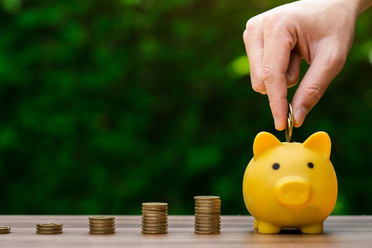 An image shows a man's hand saving money.