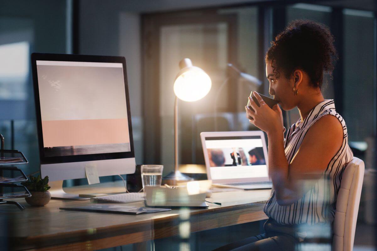 A picture shows a woman sipping a coffee while working.