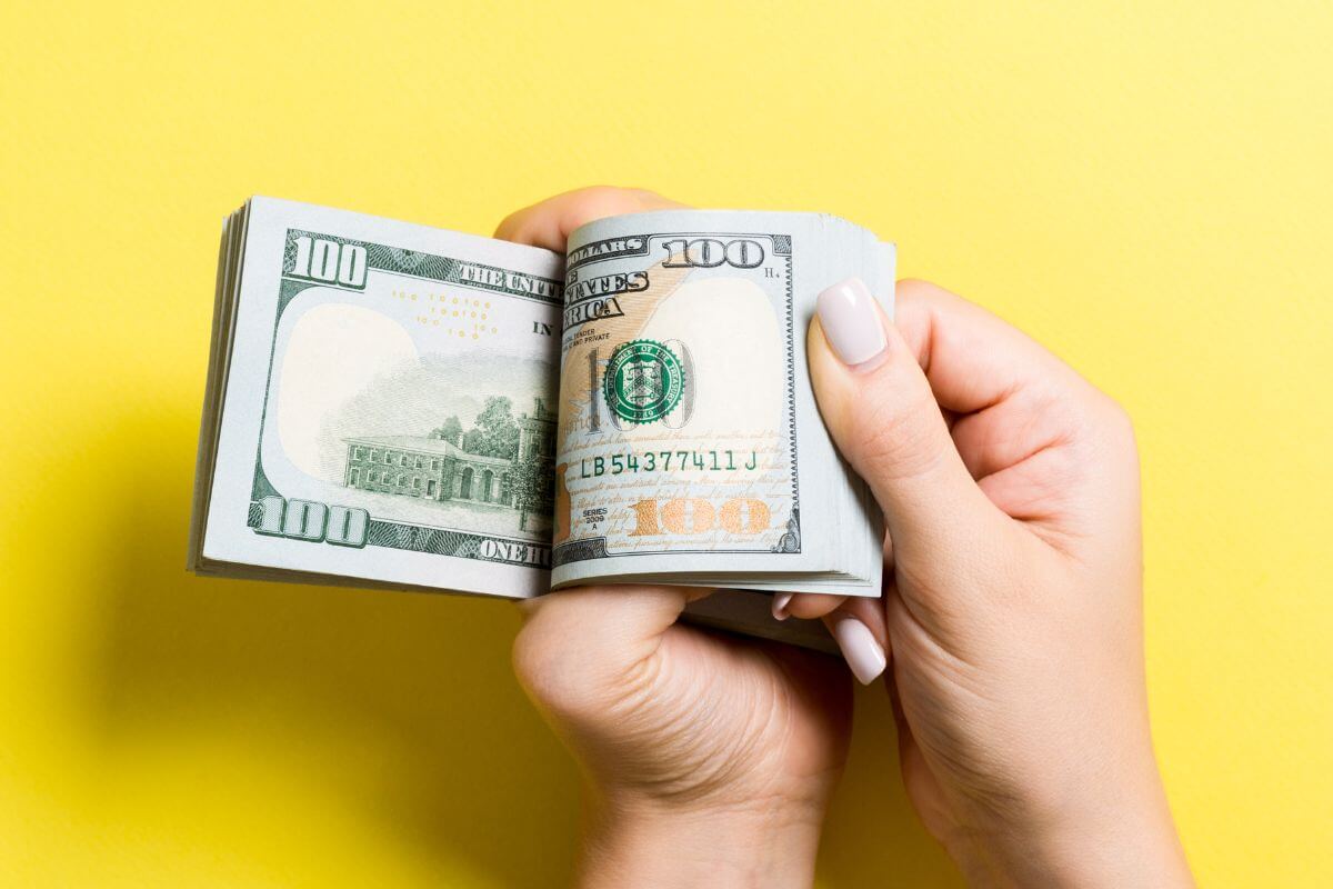 An image shows a woman's hand holding money.