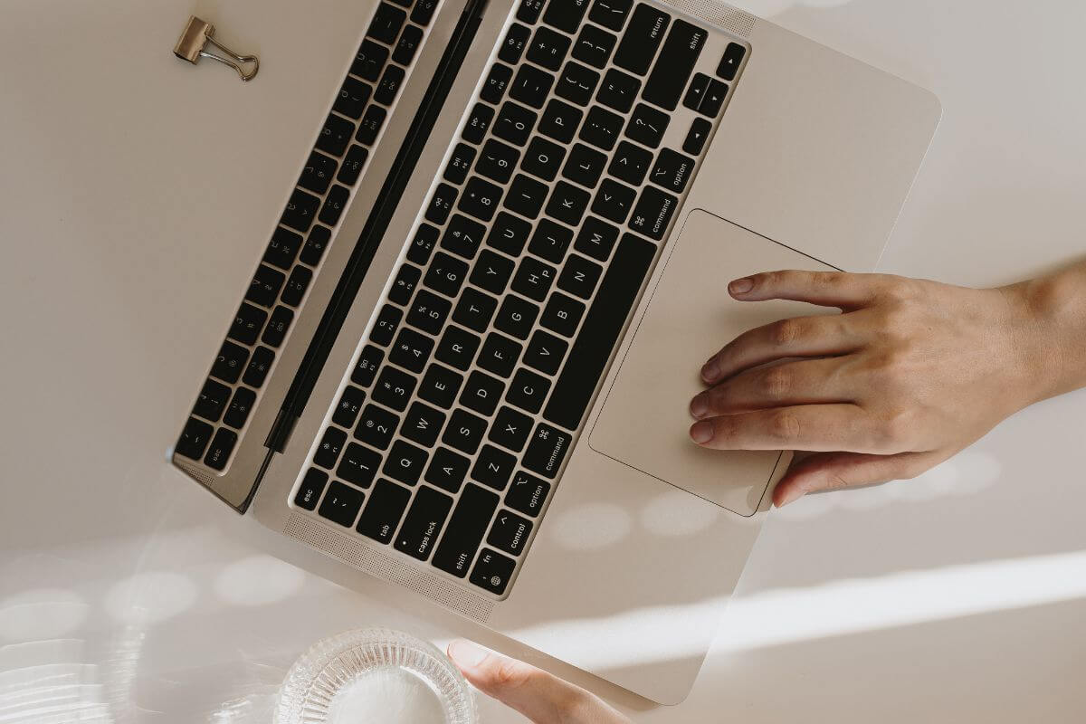 An image shows a woman's hand using a laptop.