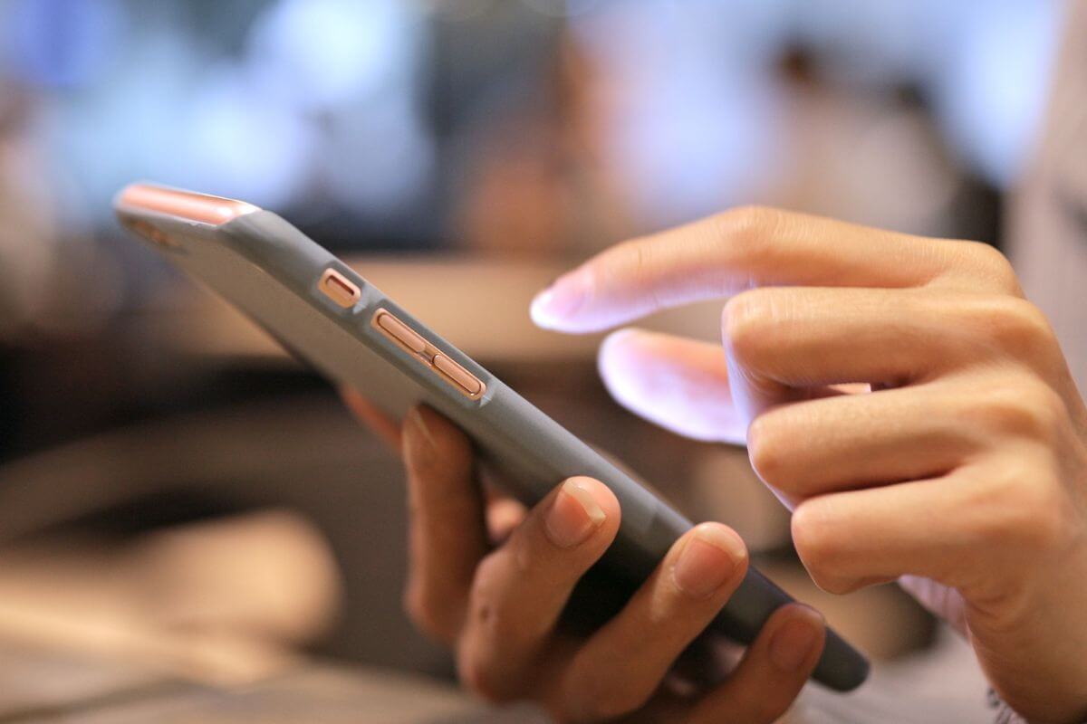 An image shows a woman's hand using a phone.