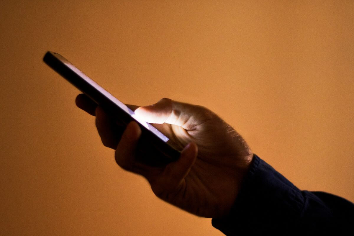A picture shows a man's hand using a smartphone.