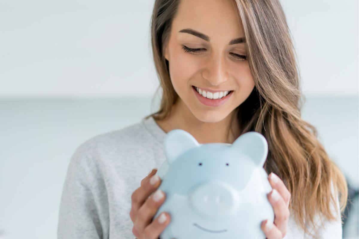 An image shows a woman holding a piggy bank.