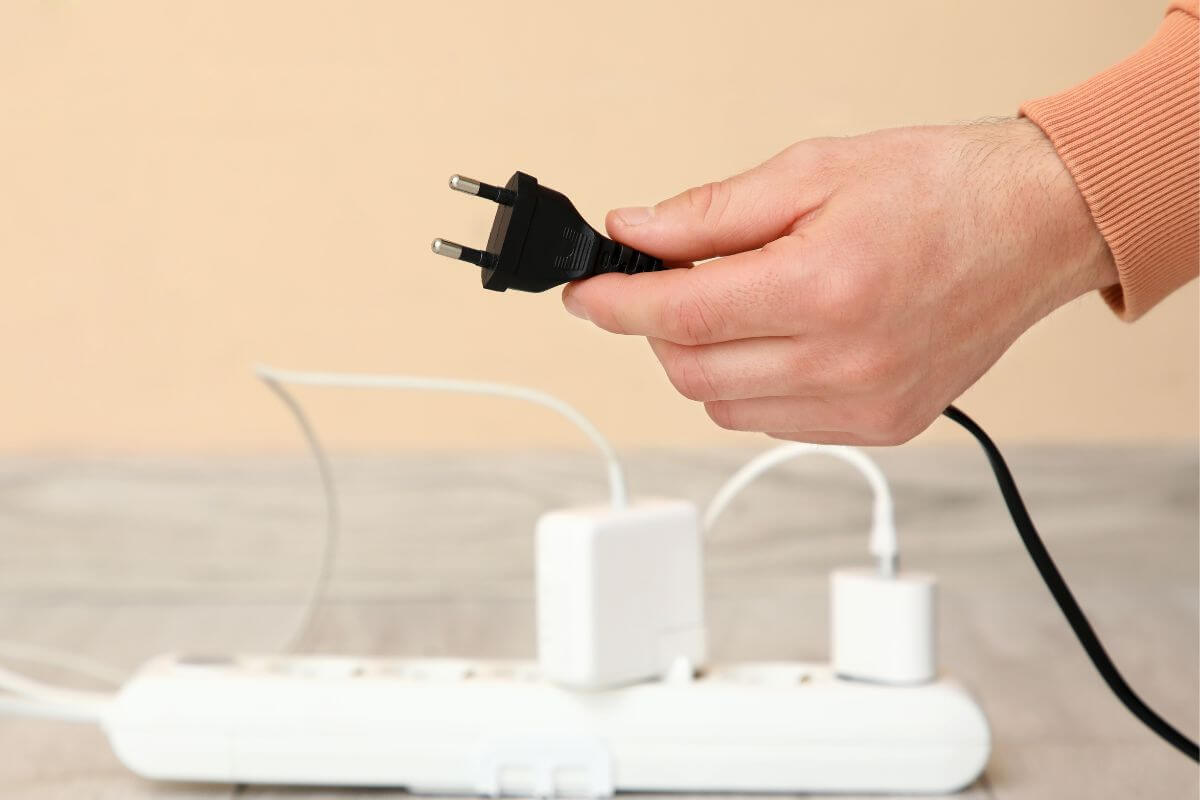 An image shows a man's hand unplugging a cord.