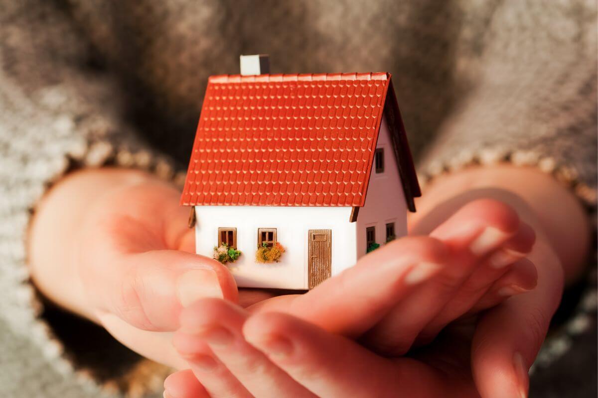 A picture of a woman's hand holding a mini house.