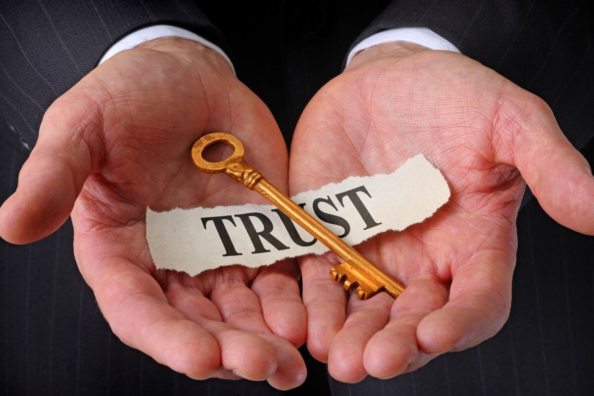 A picture of a paper with trust wording on a man's hand.