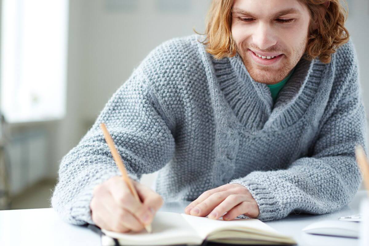 A picture of a man writing in a notebook.