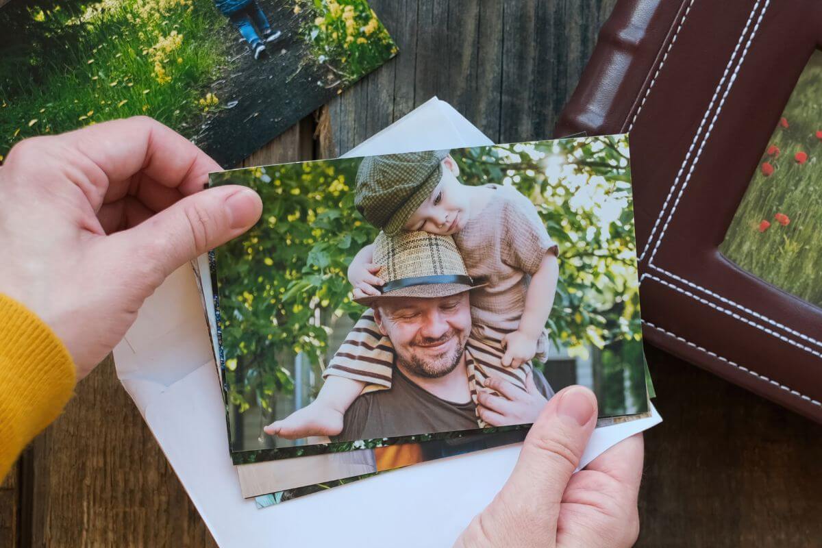 An image shows a woman's hand holding printed photos.