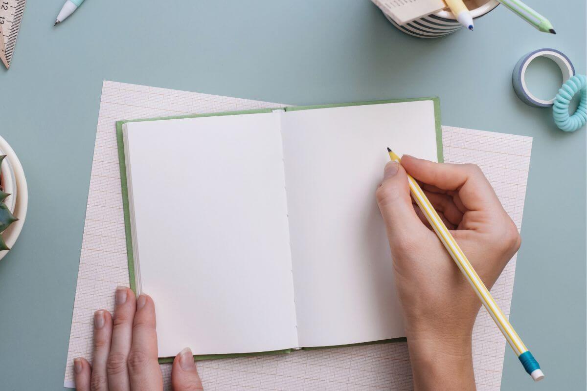A picture shows a woman's hand writing in a notebook.