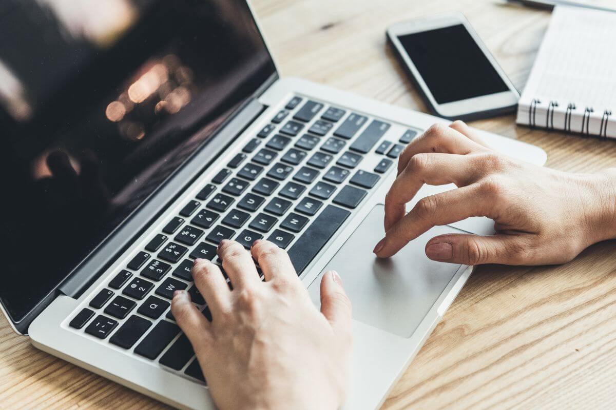 An image shows a woman's hand using a laptop.