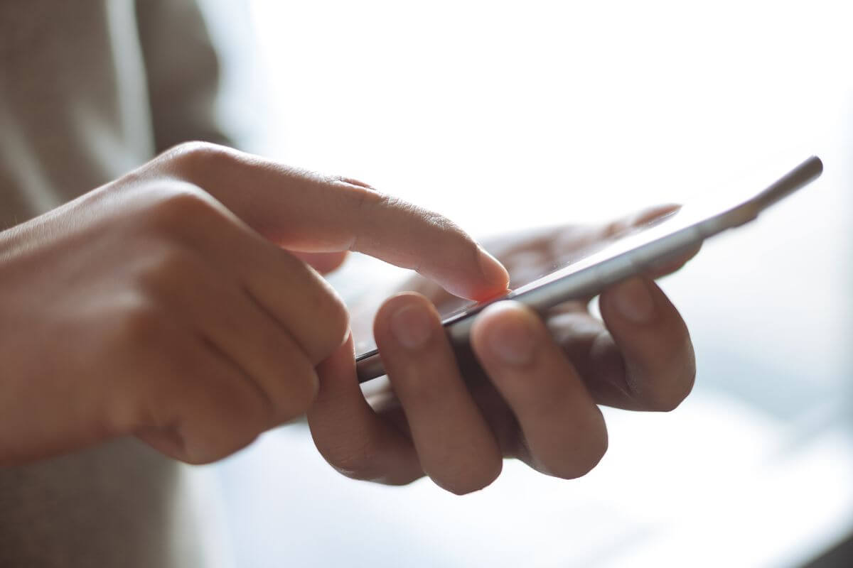 A picture shows a man's hand using a phone.