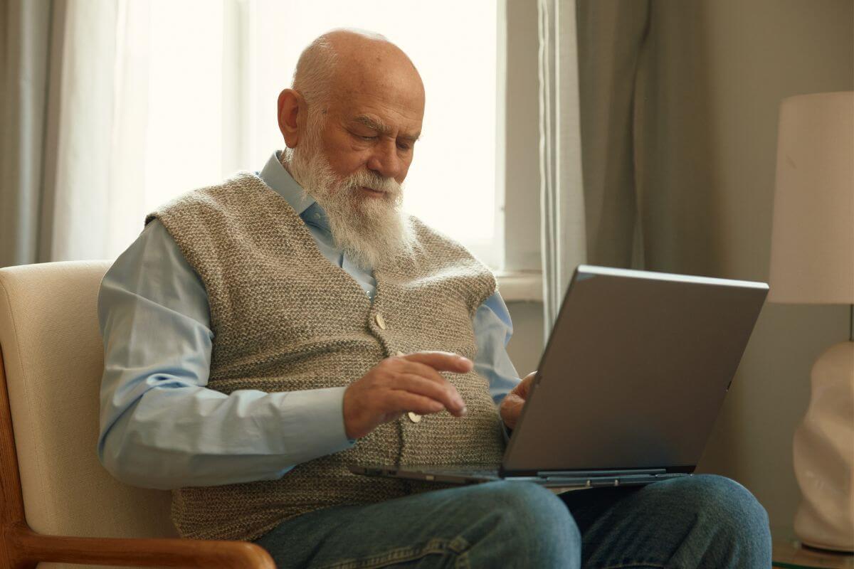 A picture of a retiree using his laptop.