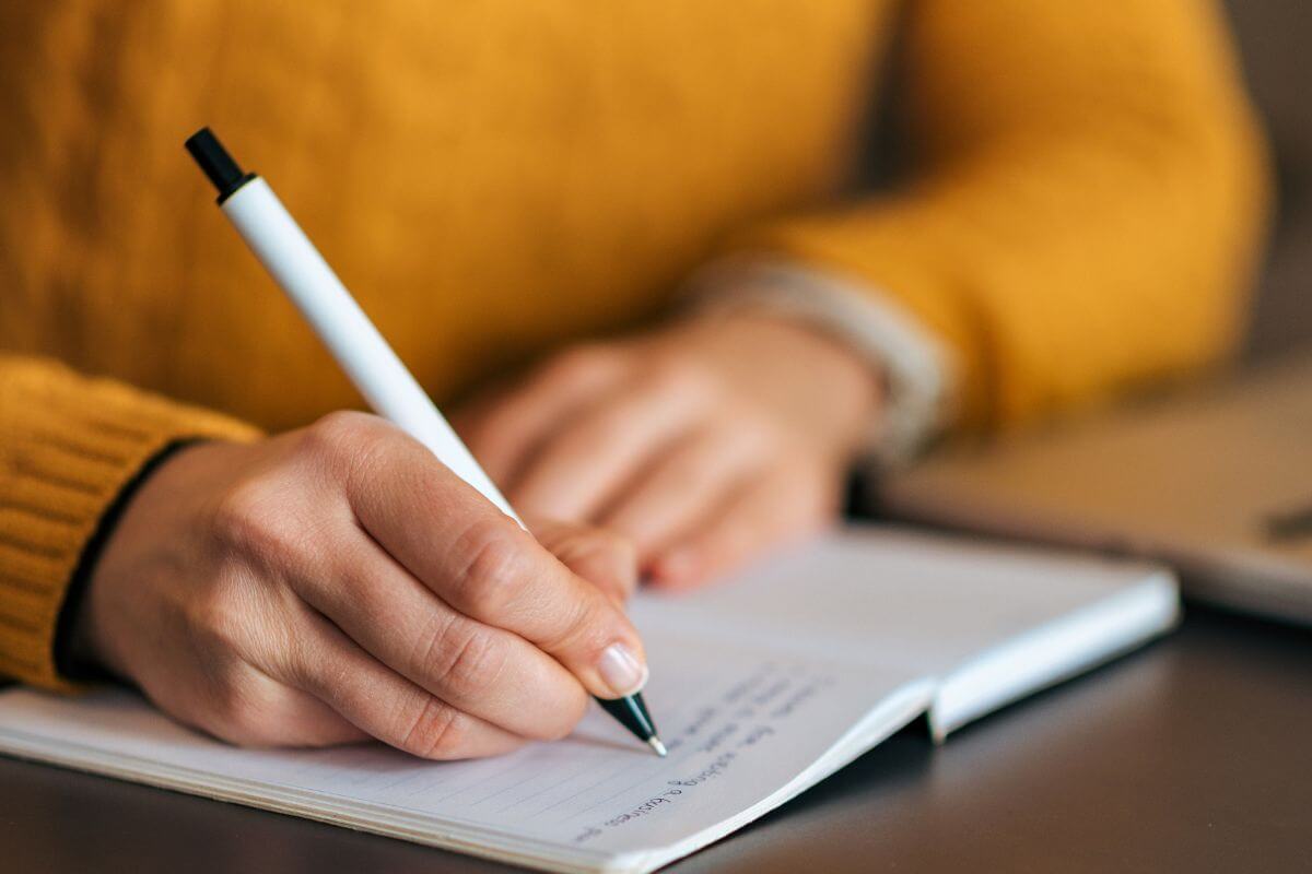 A picture shows a woman writing in a notebook.