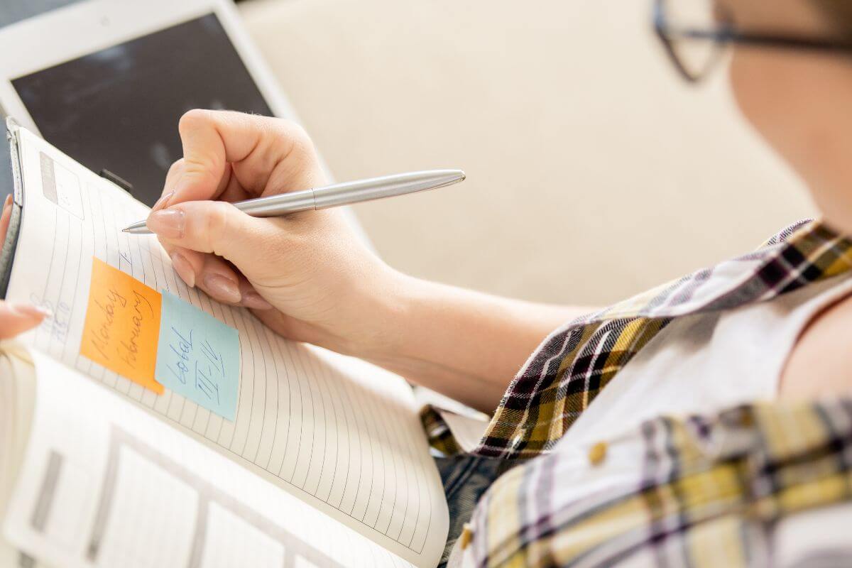 A picture of a woman writing in a notebook.