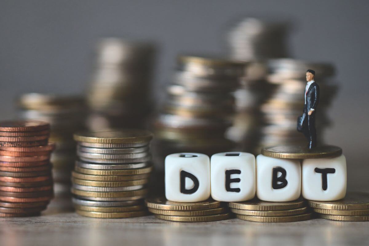 A picture shows stacks of coins and debt wording.