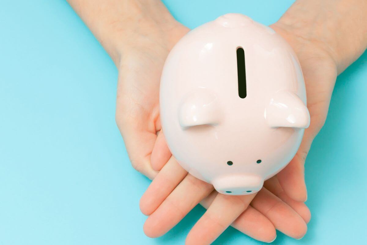 A picture shows a woman's hand holding a piggy bank.