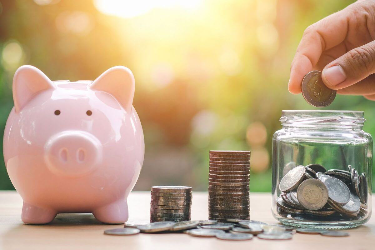A picture of a man's hand saving money in a jar.