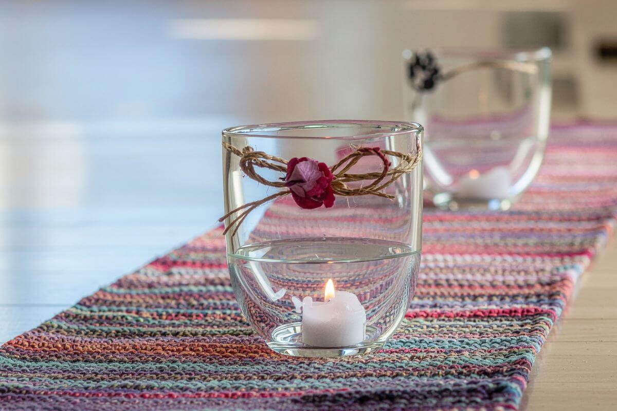 A picture shows a table runner with glass of candles.