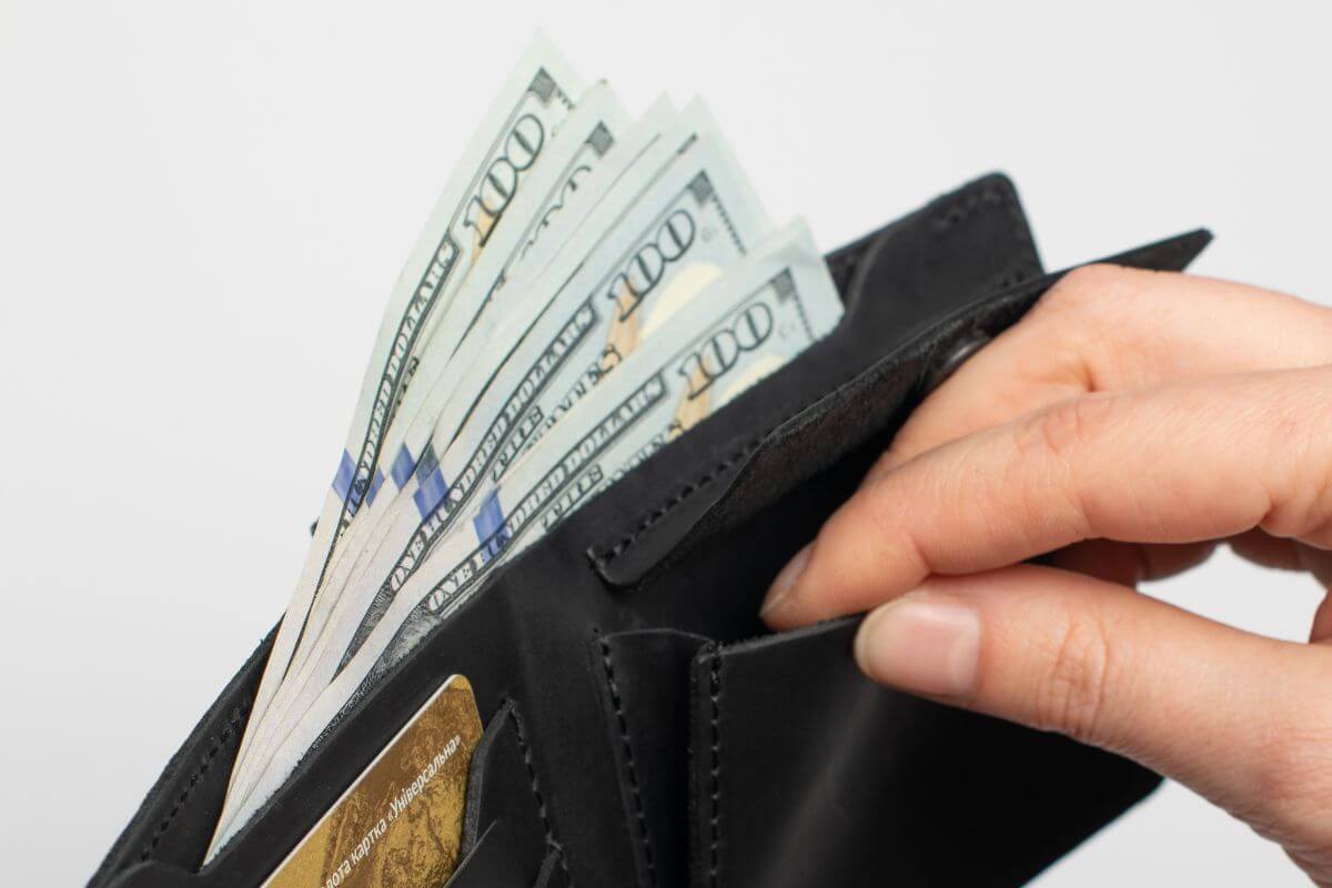 A picture of a woman's hand holding a wallet with money.