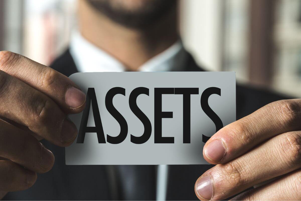 A picture of a man holding a paper with asset wording.