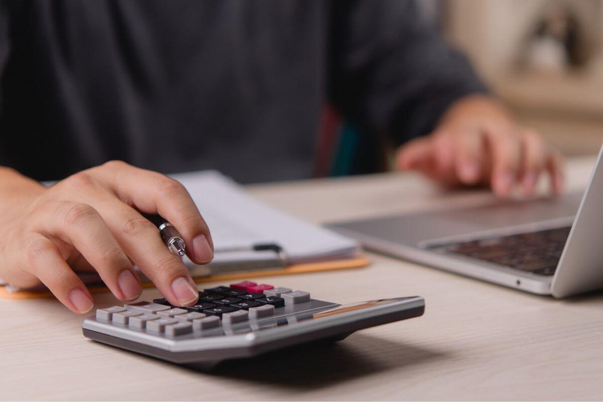 A picture of a man using a calculator and a laptop.