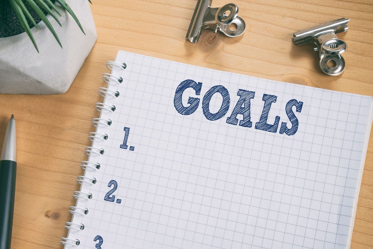 An image shows a notebook with goals written on it.