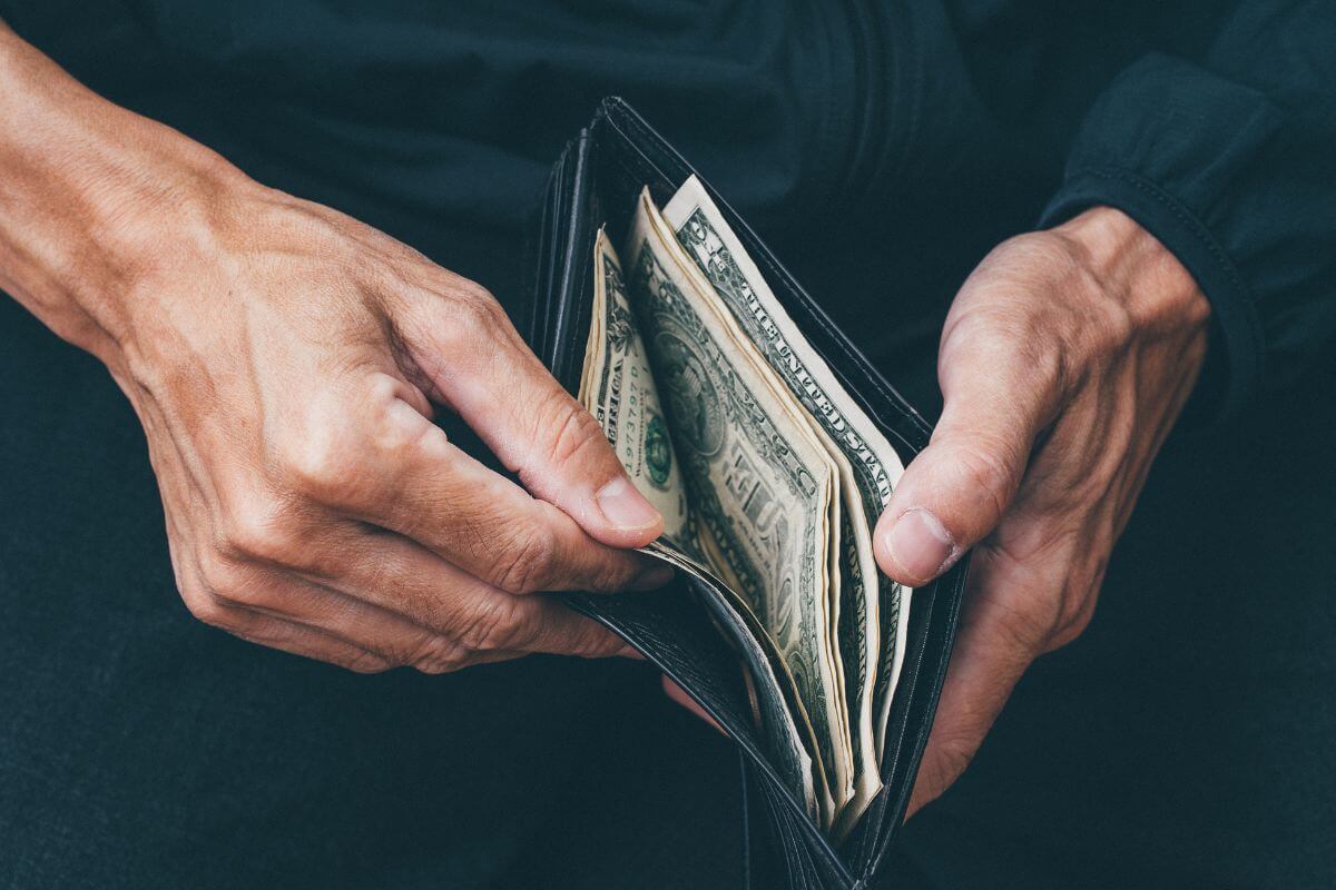An image of a man opening his wallet with money.