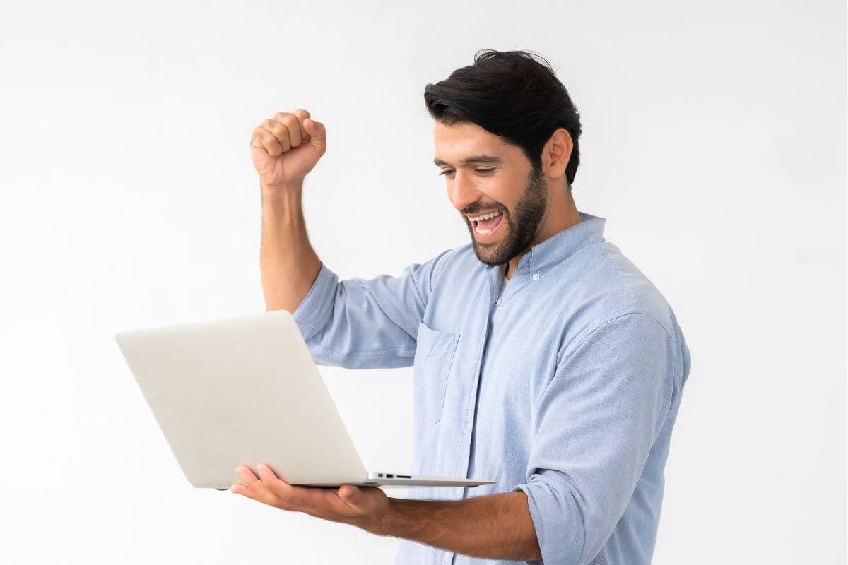 A picture shows a happy man holding a laptop.