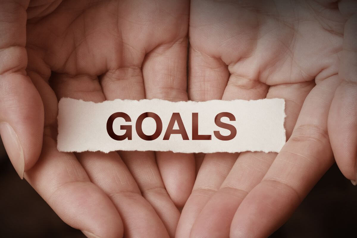 A picture shows a woman's hand holding a paper with goals wording.