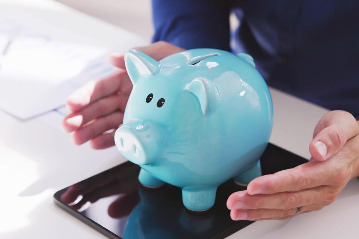 A picture of a man's hand showing his piggy bank.