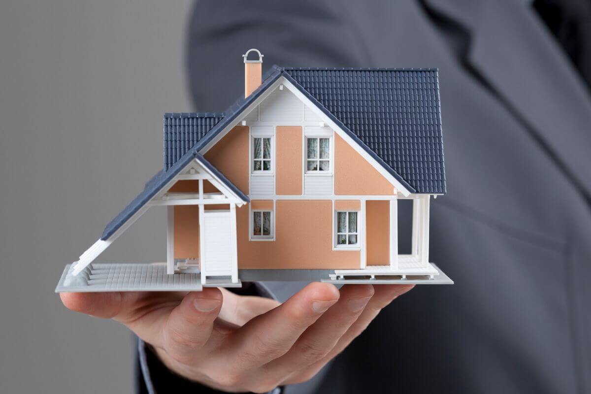 An image of a man's hand holding a mini house.