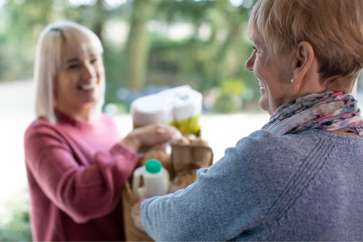Une femme aidant son voisin avec une course.