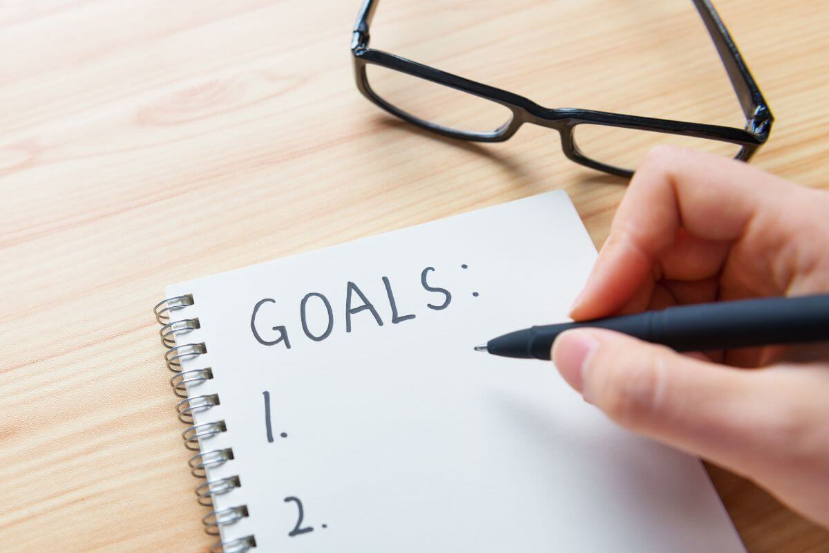 An image shows a woman writing her goals.