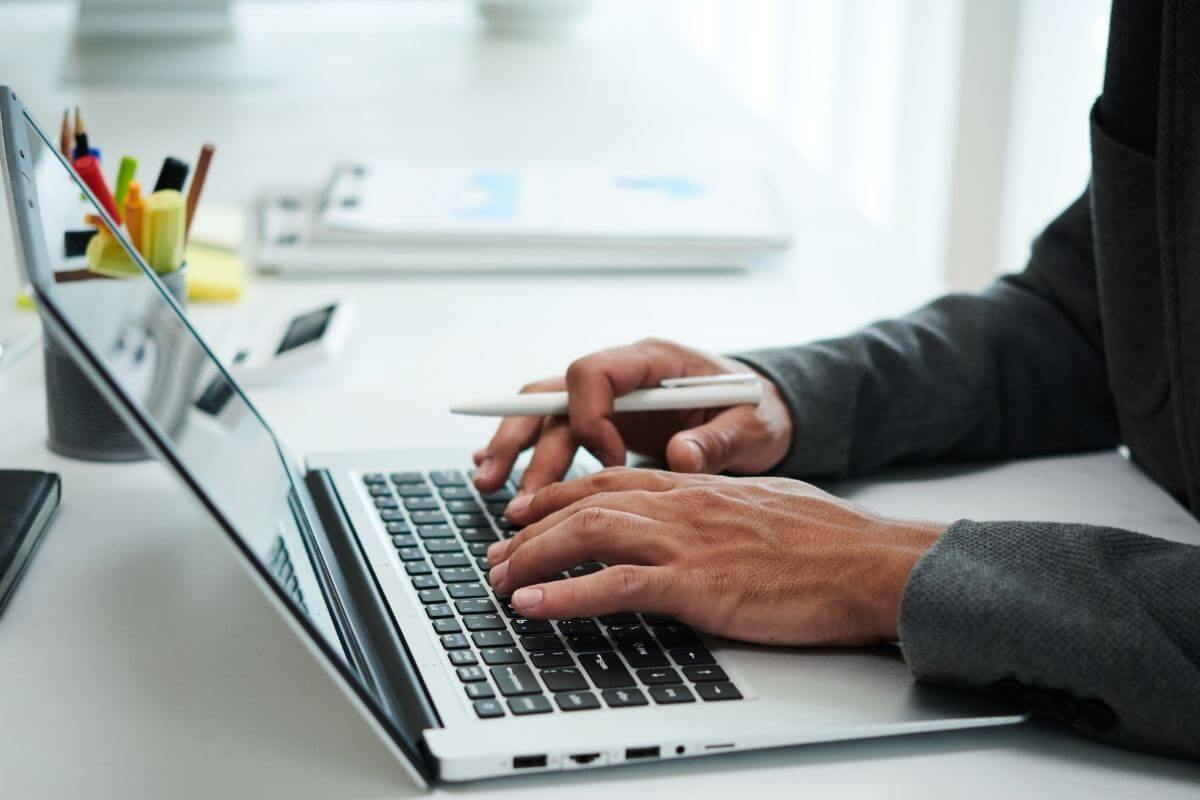 A picture of a man's hand working on a laptop.