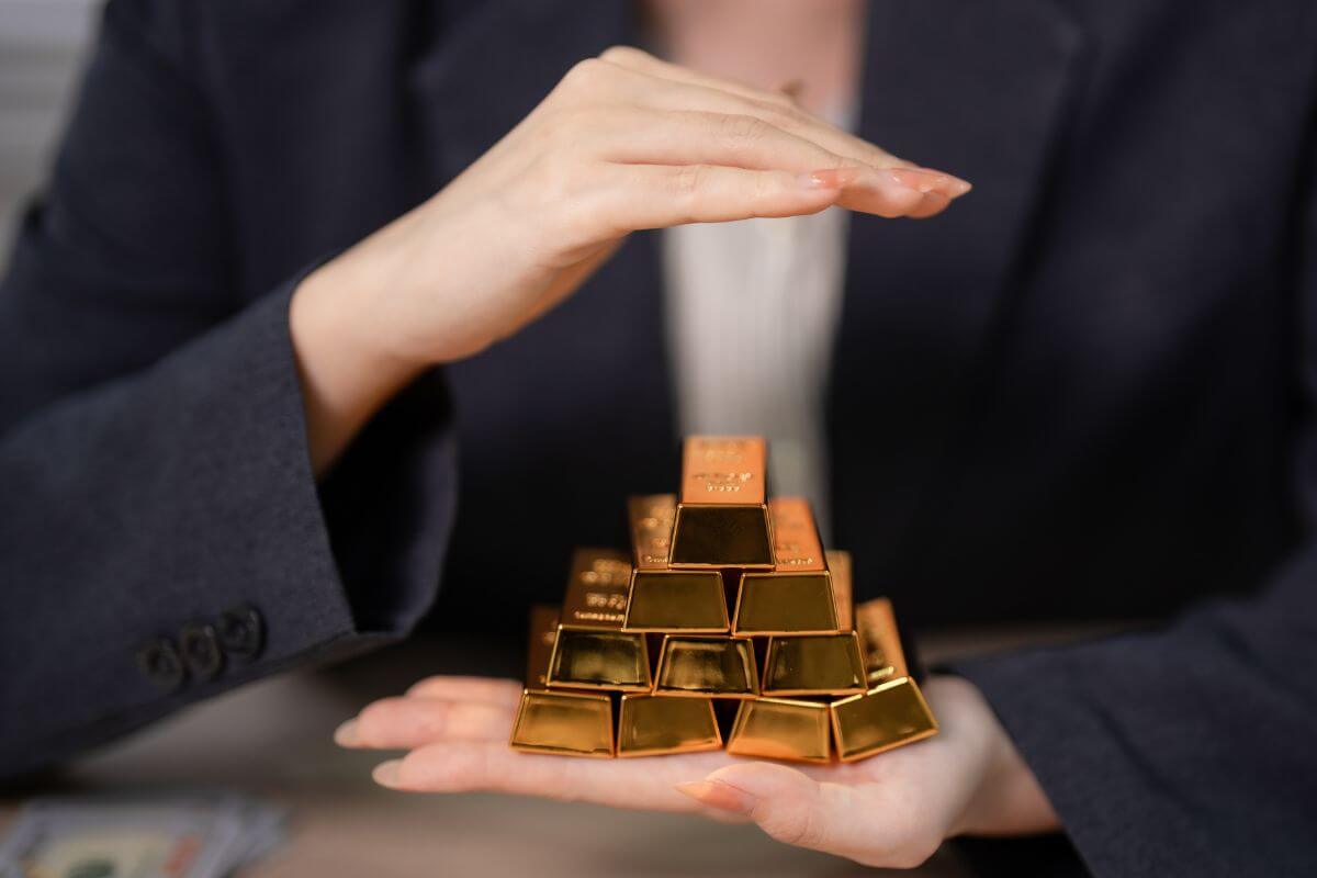 An image shows a woman holding gold bars.