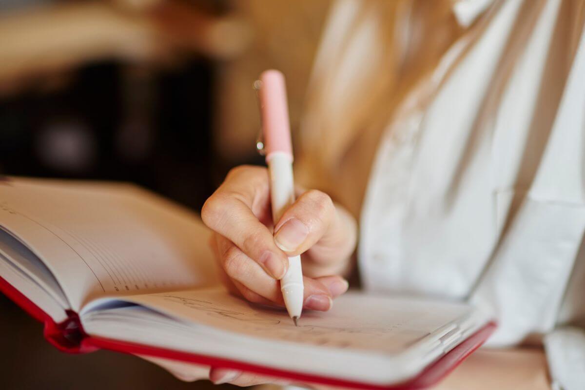 A picture shows a woman writing something in a notebook.