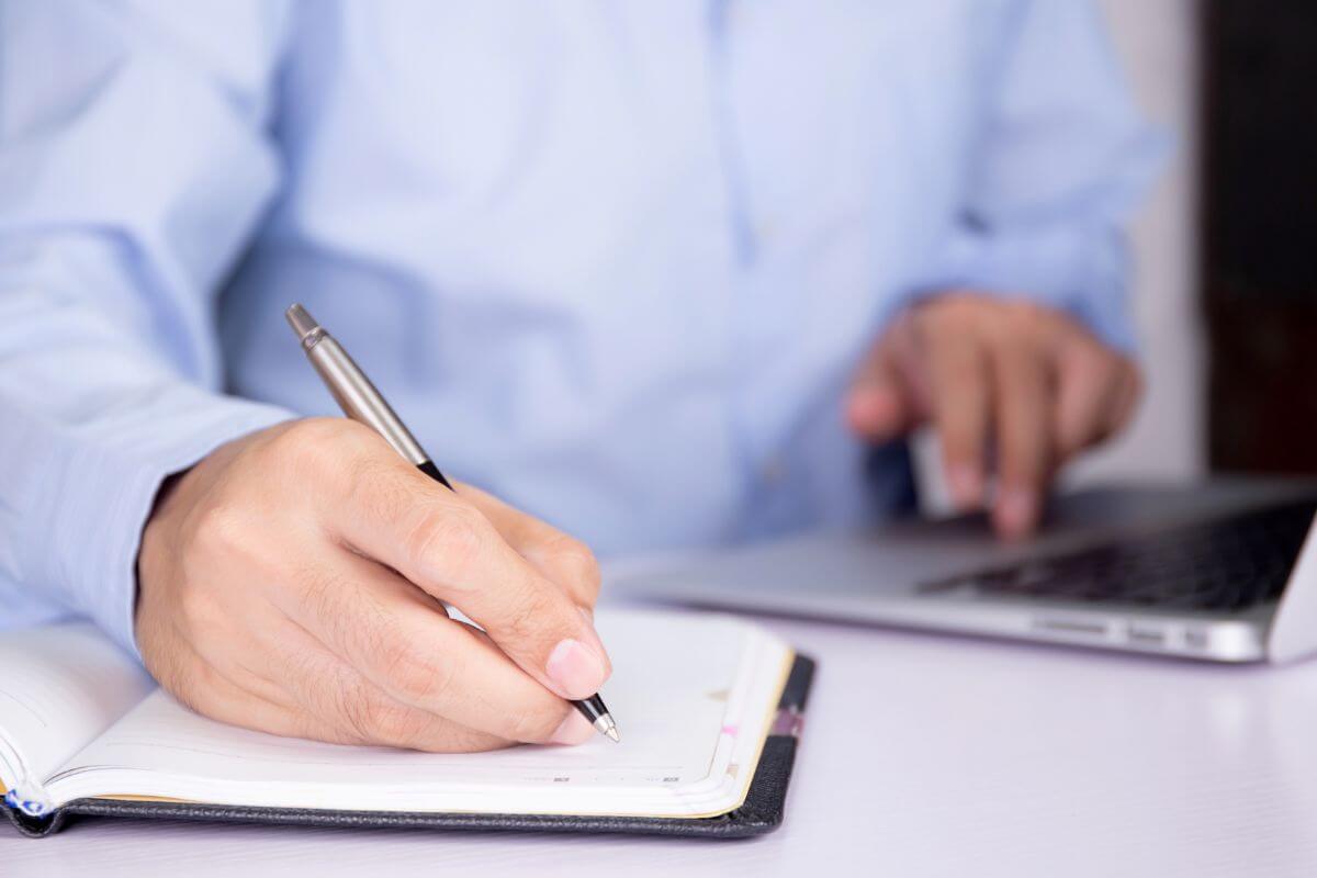 A picture of a man's hand taking notes on something.