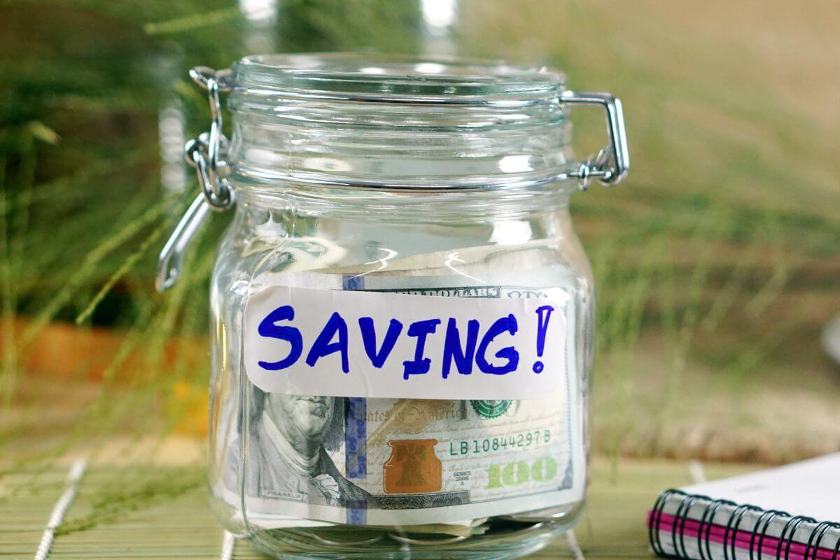 A picture of a jar with money and saving wording.