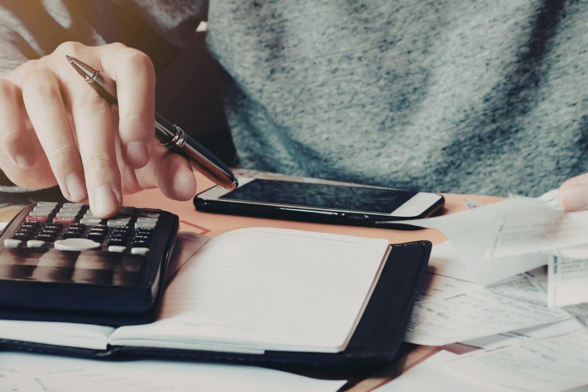 An image shows a woman calculating her expenses.