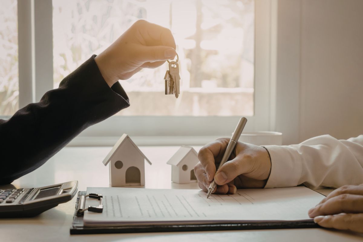 An image shows someone buying a house and signing a document.