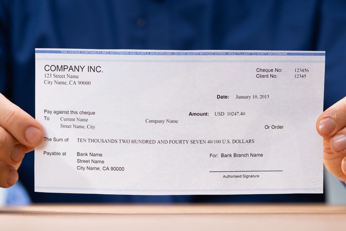 A picture shows a man's hand holding a paycheck.