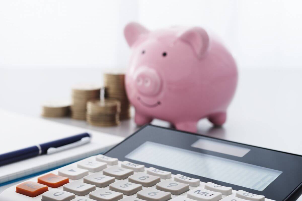 A photo shows a piggy bank, money and a calculator.