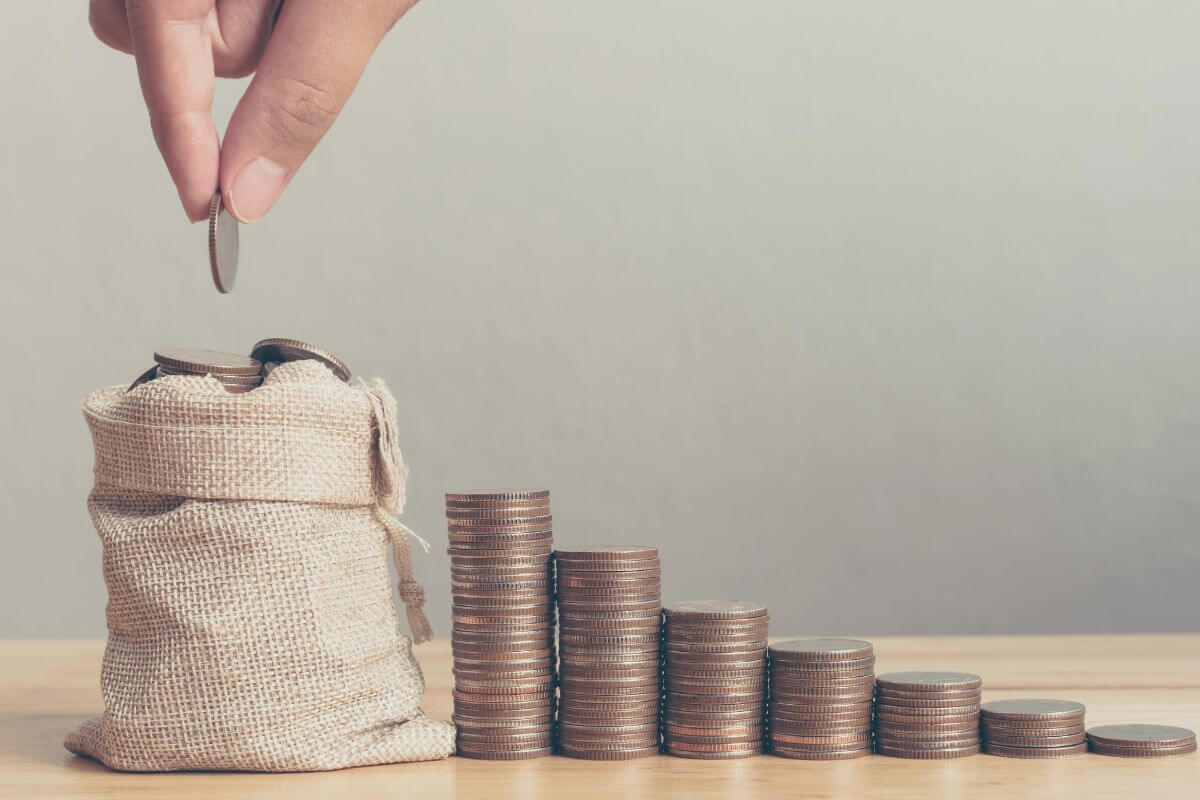 A photo shows the hand of a woman saving money.