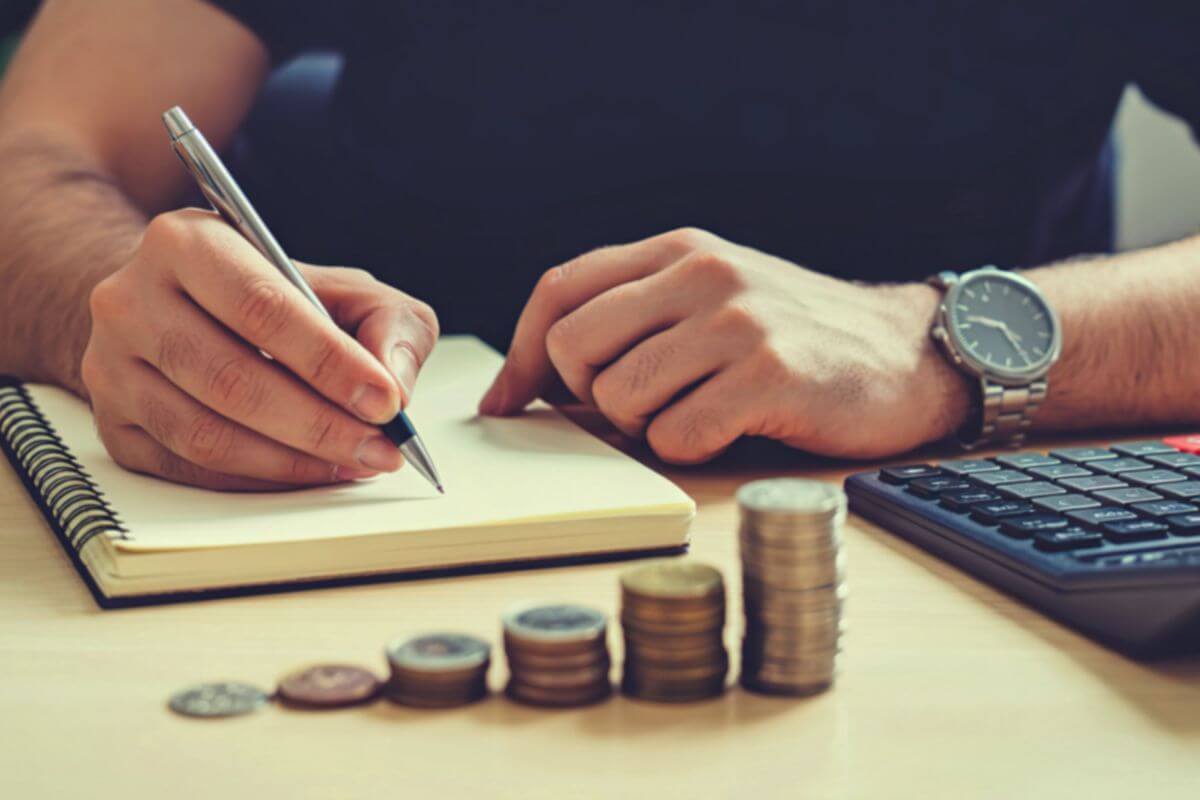 A picture tells about a man writing in a notebook.