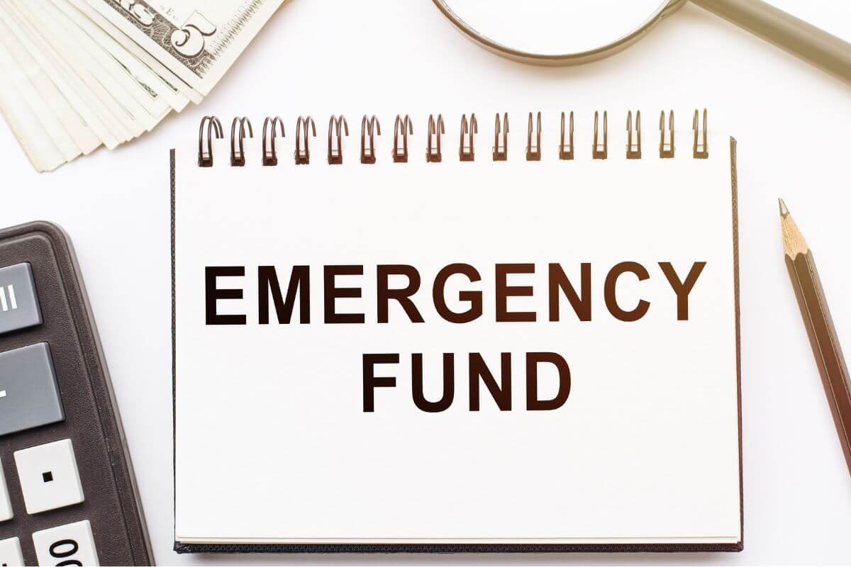 An image shows a notebook with an emergency fund written on it.