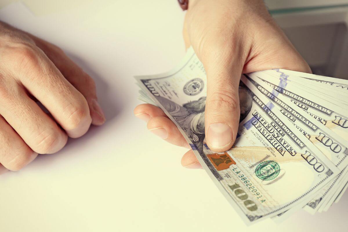 An image shows a man's hand holding money.