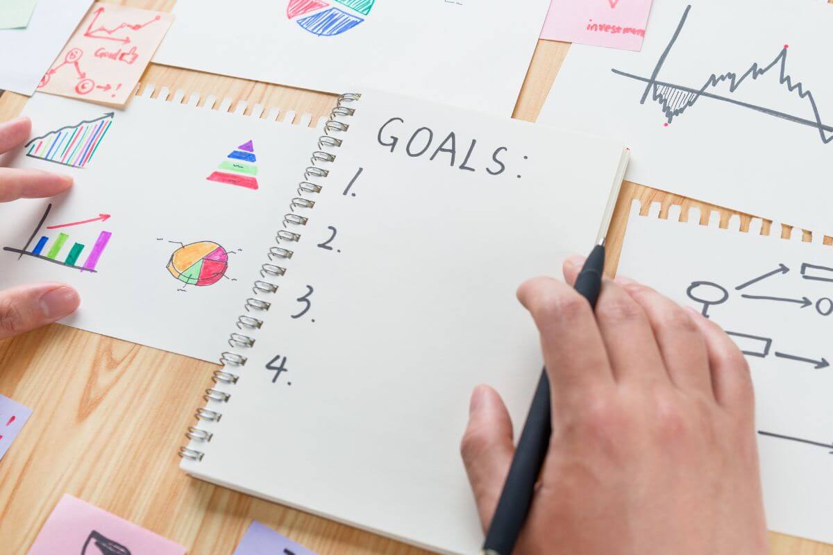 A picture of a man writing his goals in a notebook.