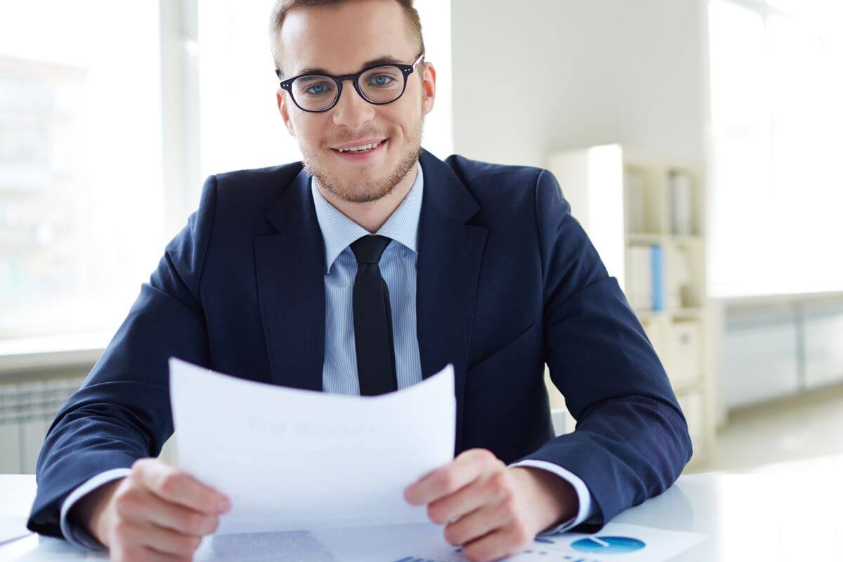 An image of a man in a suit holding a paper.