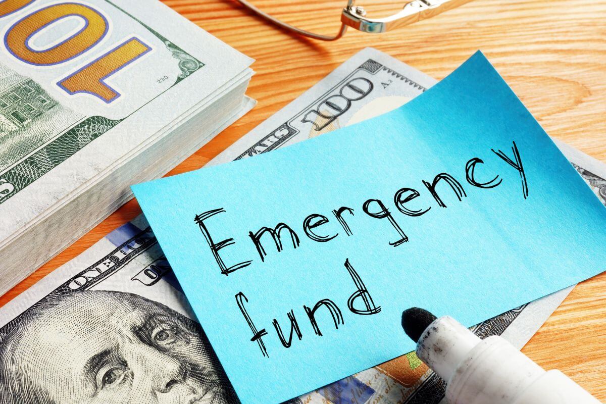 A picture shows money and a paper with the wording 'emergency fund'.